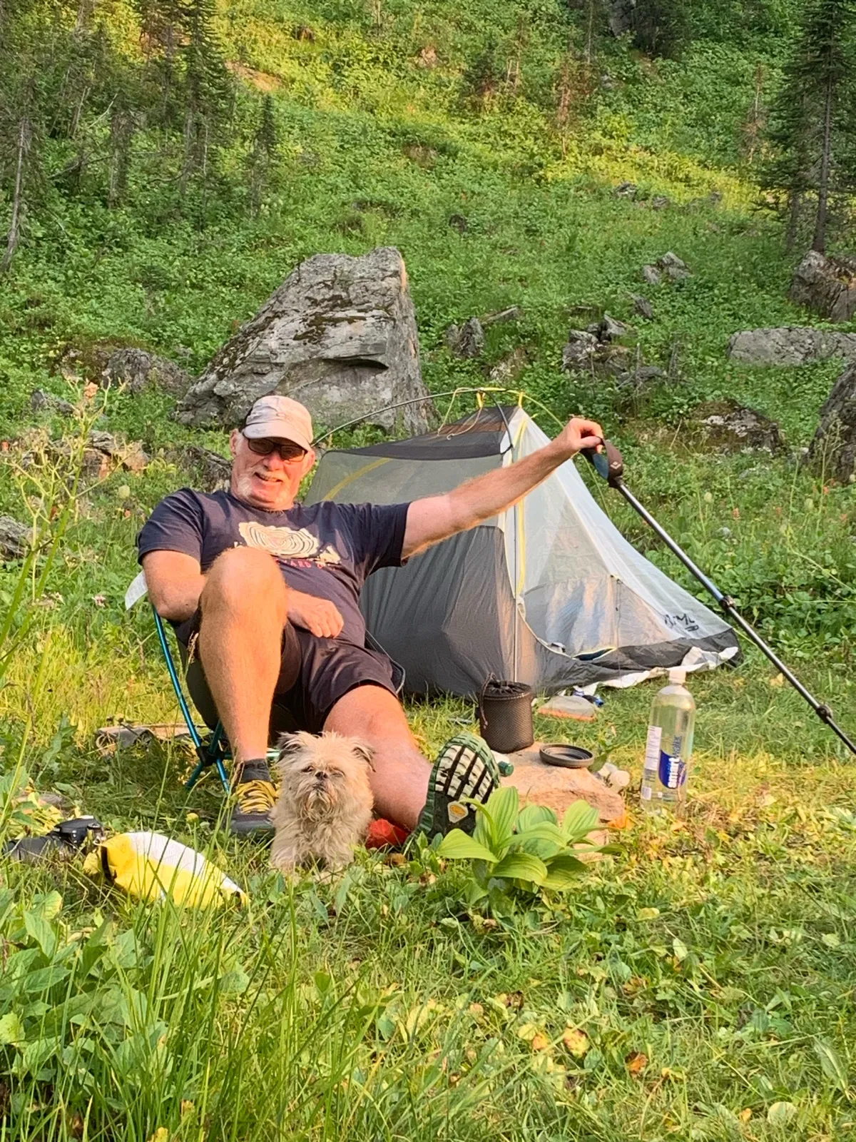 bio Chris Hewko at camp beside his tent on a mountainside, his dog at his feet