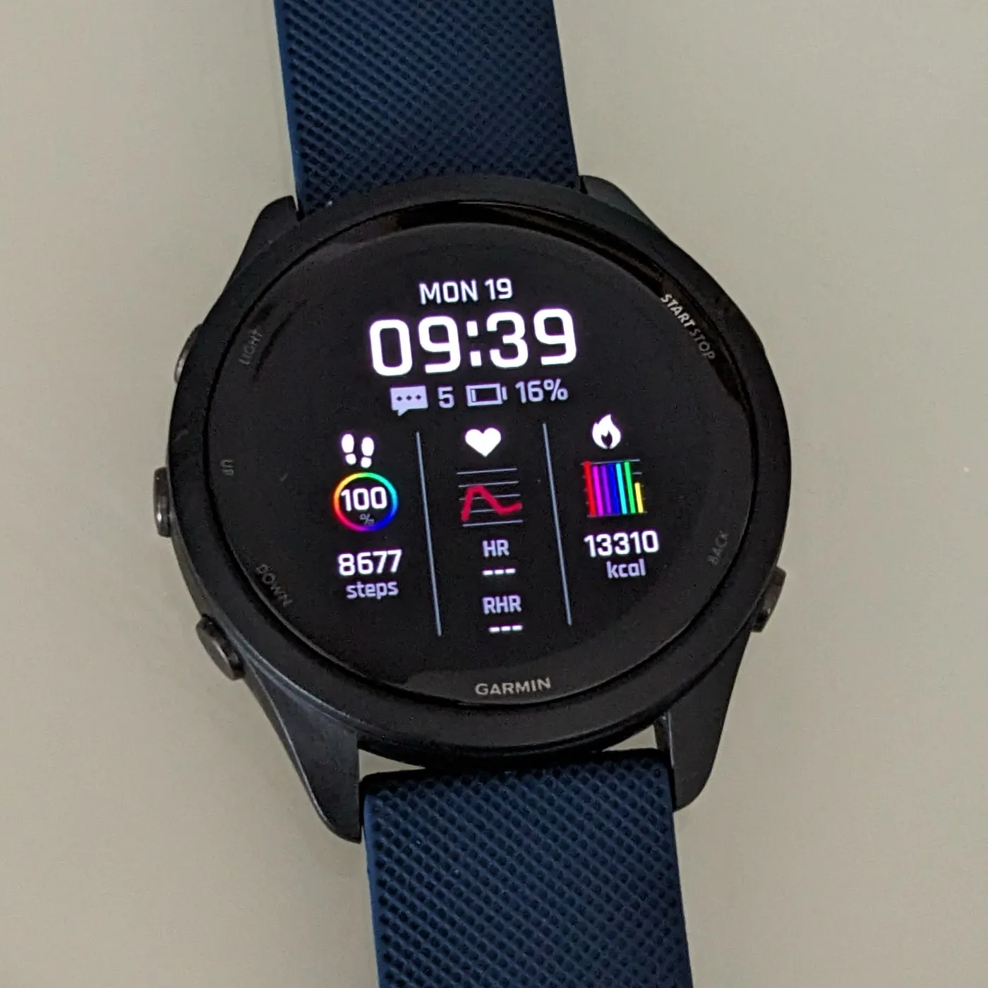 A Garmin Forerunner 265, its screen showing steps, heart rate and calories