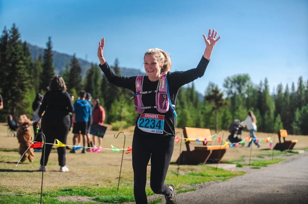 bio Tamra Sutherland crossing a finish line, arms raised